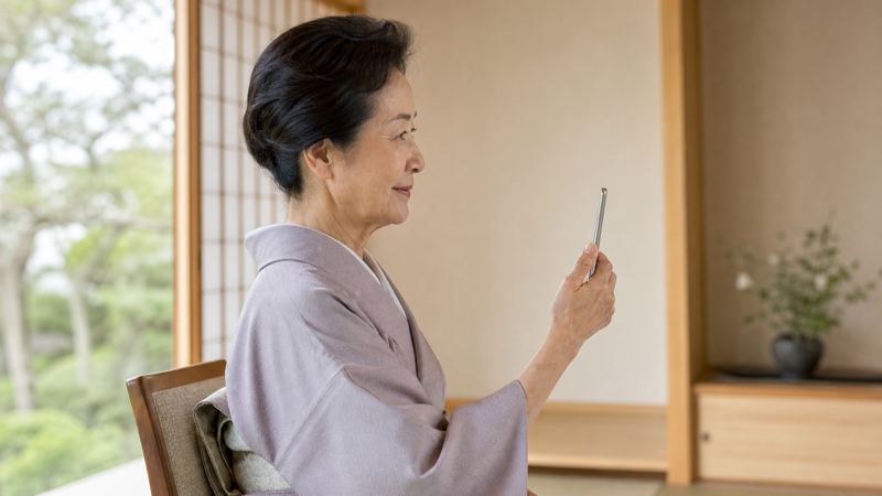和室で静かにスマホを持っているシニア女性